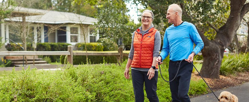 Older couple walking dog wearing fitbit