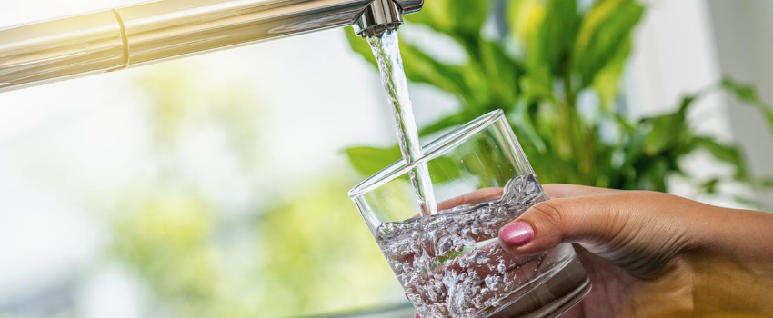 A person filling a glass with drinking water